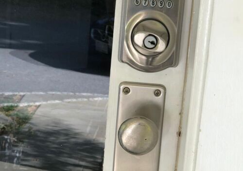 Keypad door lock and traditional handle on a residential door, showcasing smart lock technology relevant to locksmith services in Bethesda, MD.