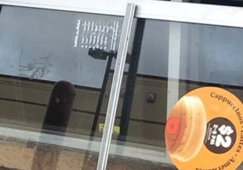 Aluminum glass door with menu and promotional sticker for cappuccinos, relevant to commercial door installation and repair services in Arlington, VA.
