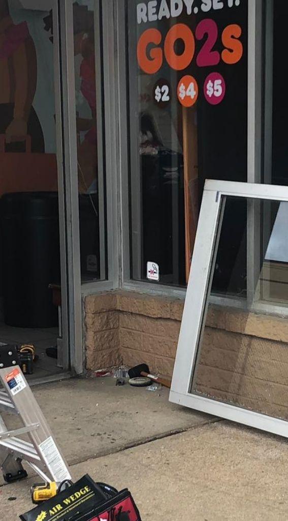 Aluminum glass door installation in progress at a commercial establishment, featuring tools and an open doorway with promotional signage.
