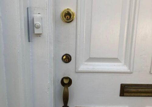 Residential front door featuring a new deadbolt lock installation, brass doorknob, and a doorbell, emphasizing enhanced security for Georgetown homes.