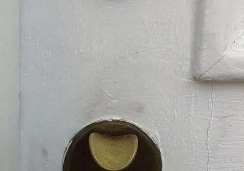 Close-up of a deadbolt lock installed on a white door, highlighting the brass cylinder and keyhole, emphasizing security features relevant to residential door upgrades by MacArthur Locks & Doors in Washington, DC.