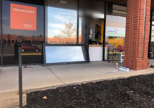 Commercial storefront door replacement in Alexandria, VA, with removed door leaning against the building, showcasing door installation service by MacArthur Locks and Doors.