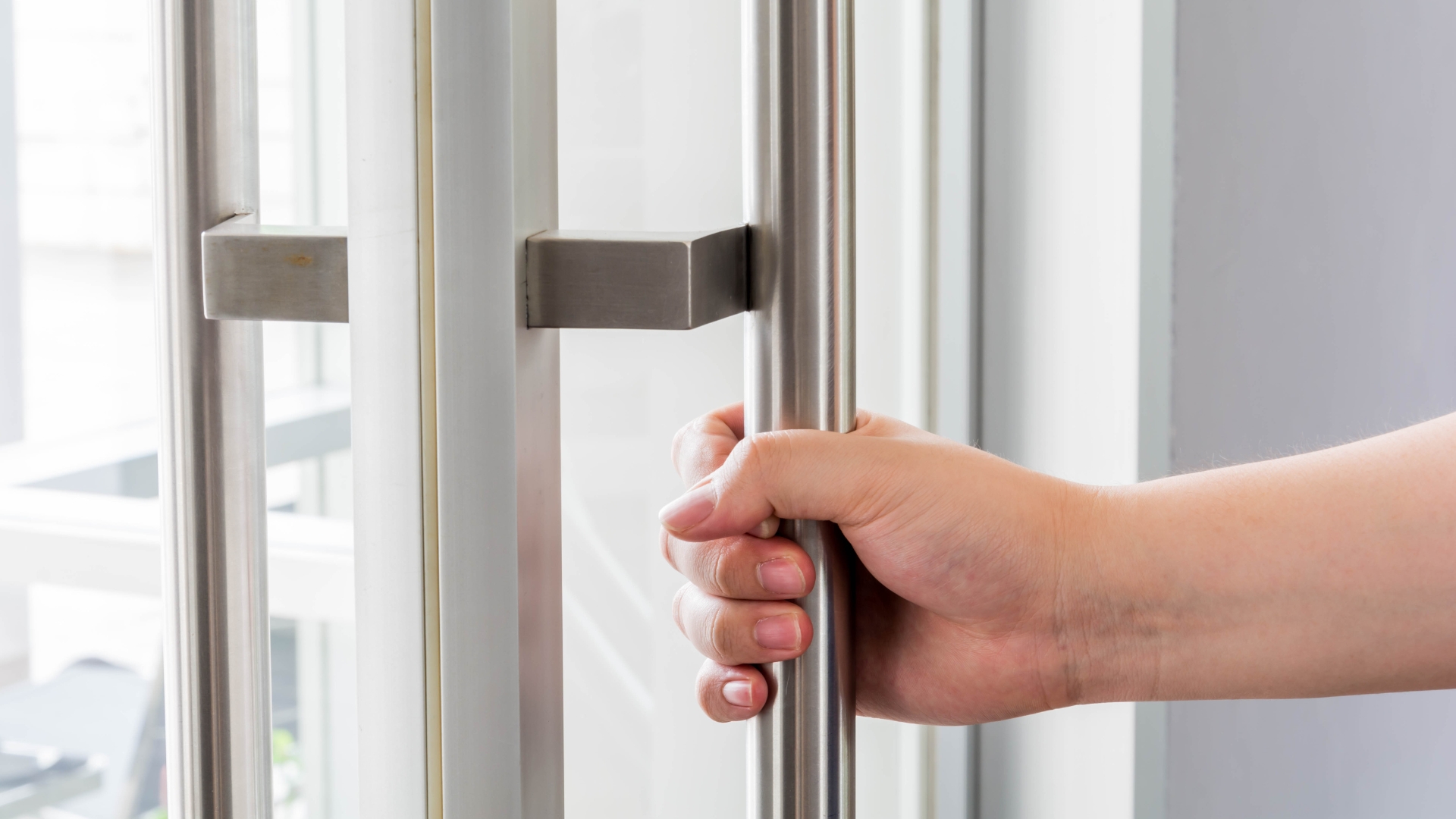 A user pulling open a glass commercial door