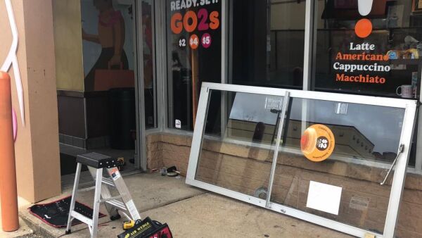 Commercial door repair in Arlington, VA, featuring an aluminum glass door being replaced outside a food establishment, with tools and a ladder visible.