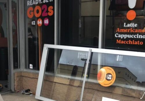Aluminum glass door installation outside a commercial establishment, featuring a menu display with coffee options and pricing, emphasizing MacArthur Locks & Doors' services for commercial door repair and installation.