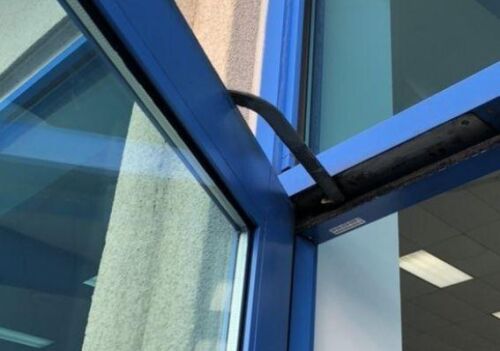 Commercial door repair image showing damaged aluminum glass door hinge in a commercial setting, highlighting the need for locksmith services in Fairfax, VA.