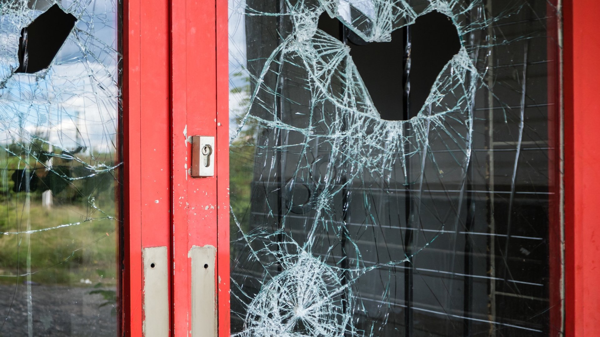 A damaged commercial door with broken glasses