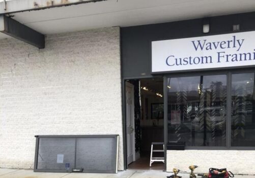 Commercial door repair service in Ellicott City, showcasing a storefront with a sign for Waverly Custom Framing, tools and equipment visible on the ground.