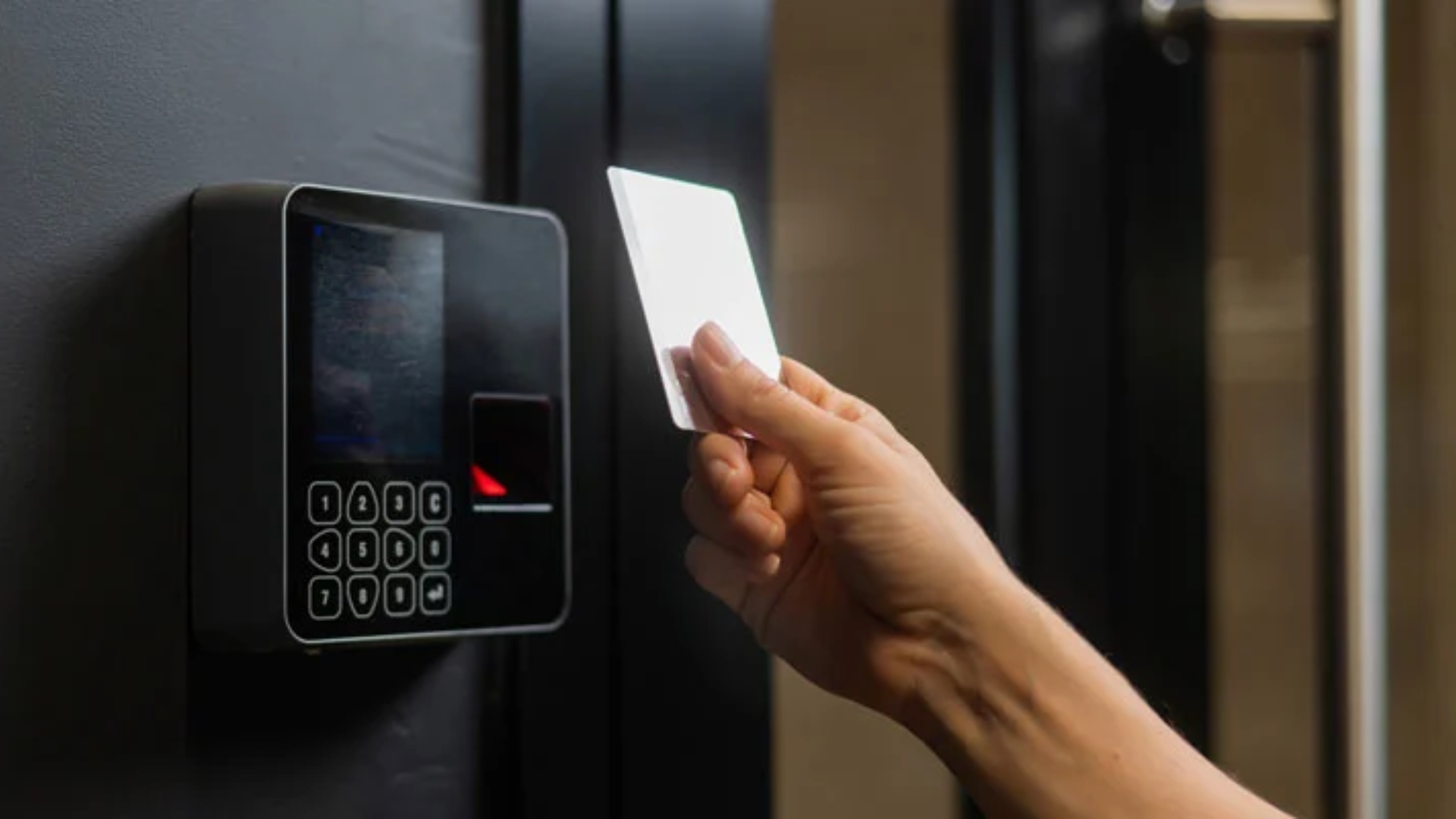 Hand swiping keycard on keypad door entry system.