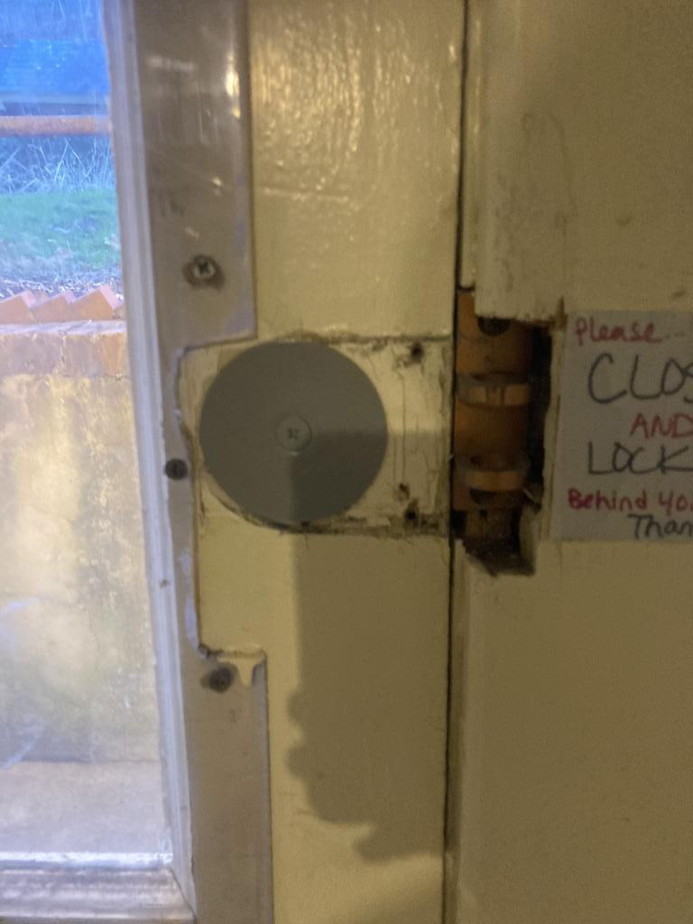 Door lock installation on a wooden door with a circular lock mechanism and a note requesting to close and lock the door, highlighting residential security.