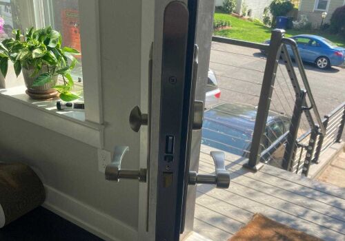 Mortise lockset installed on a residential door, showcasing the lock mechanism and handles, with a view of the exterior and nearby plants, relevant to MacArthur Locks & Doors' lock repair services.