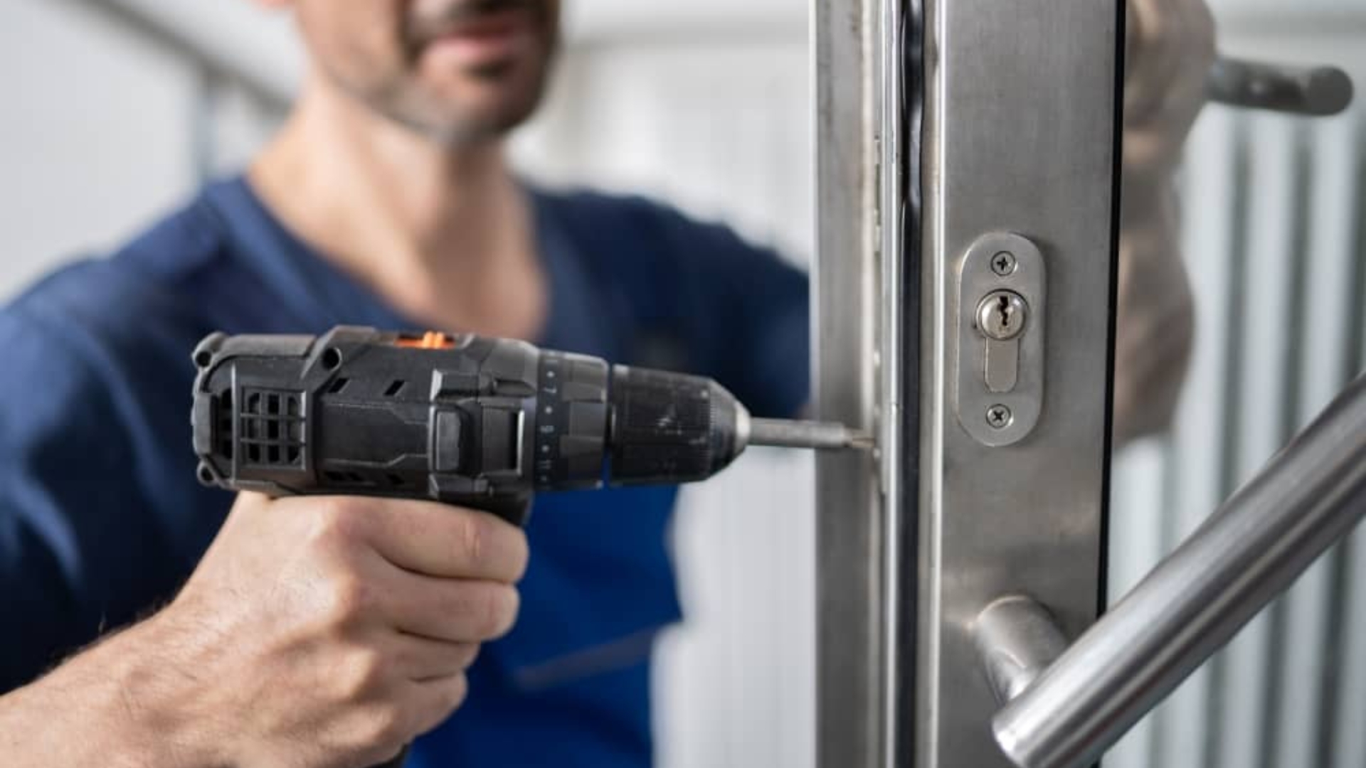 Man using a power drill to repair a commercial door lock, emphasizing the importance of timely lock maintenance and repair services for business security.