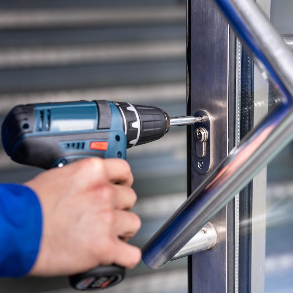 Commercial locksmith in DMV performing lock installation or repair on a metal-framed glass door